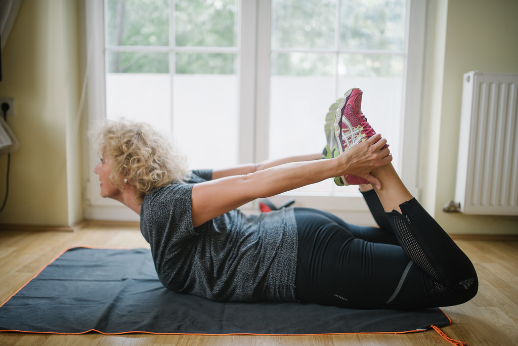 Senior woman practicing home exercise near window.